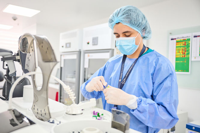 Un doctor vestido de bata y con tapabocas se encuentra tomando un tubo de ensayo