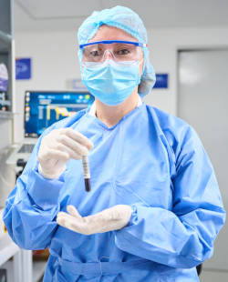 Se ve a una profesional de la salud vestida con elementos de protección quirúrgico, incluido: cabeza, lentes de protección, tapabocas y guantes de ...