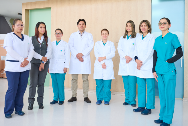 Se observan 7  profesionales de la salud posando de pie frente a la camara entre los cuales se encuentran doctores, enfermeras y recepcionistas.